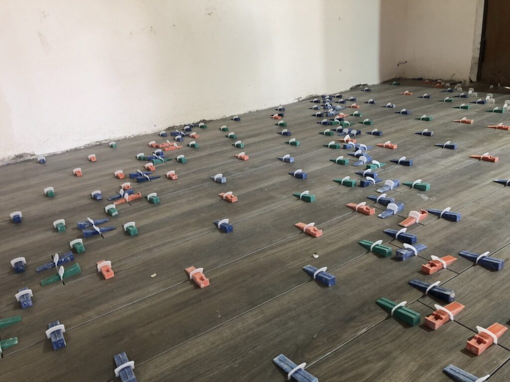Pavimento effetto legno durante la posa con distanziatori e cunei di livellamento